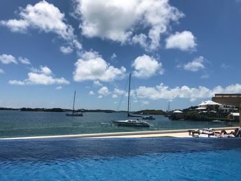 Sailboats moored in sea against sky