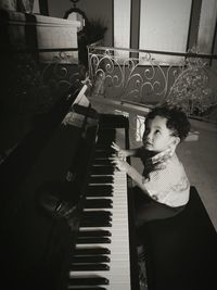 High angle view of cute boy playing piano at home