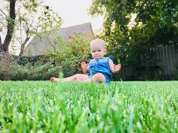 Portrait of cute baby girl sitting on field