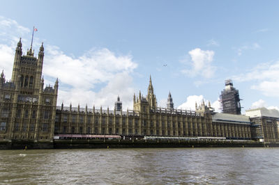 View of buildings by river against sky in city