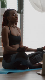 Young woman looking away while sitting on table