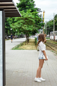 Rear view of woman standing on footpath