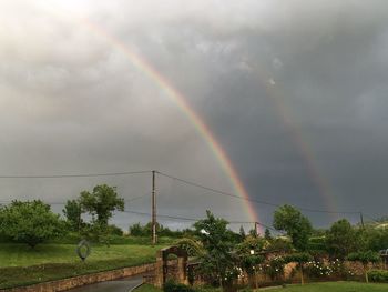 Scenic view of rainbow over trees against sky