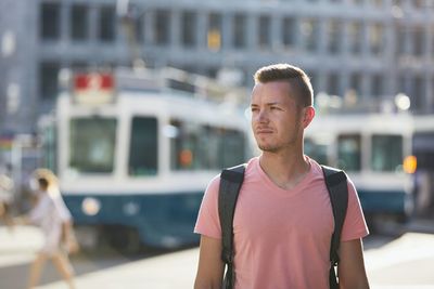 Portrait of young man looking away in city