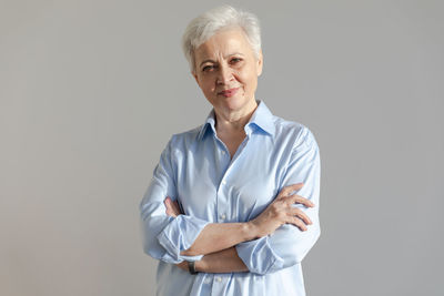 Portrait of female doctor standing against wall