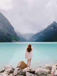 Rear view of woman standing on rocks against mountain