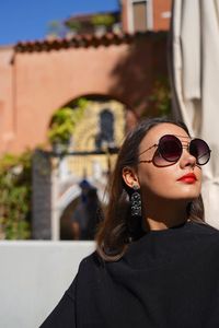 Portrait of young woman wearing sunglasses standing outdoors