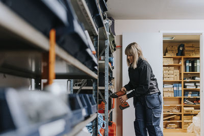 Female worker taking equipment from shelf