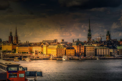 View of buildings at waterfront against cloudy sky