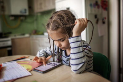 Pretty stylish schoolgirl studying math during her online lesson at home, online education concept