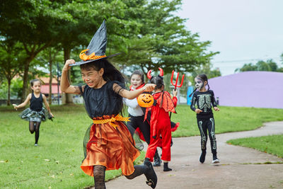 Girls in halloween costumes running on footpath at park