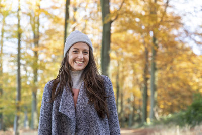 Portrait of smiling woman standing against trees during autumn