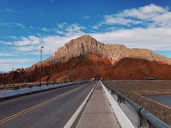 Road leading towards mountain against sky