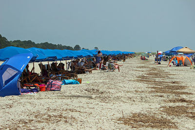 People at beach against clear blue sky