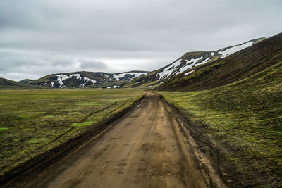 Road leading towards mountains against sky