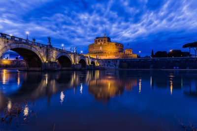 Illuminated bridge over river against sky at night