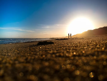 Surface level of beach against sky during sunset