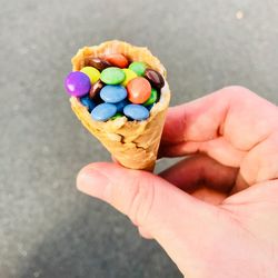 Cropped image of hand holding ice cream cone with candies