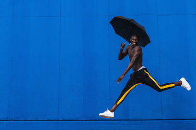 Full length of shirtless boy against blue wall