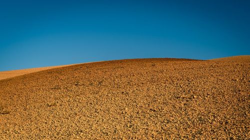 Scenic view of desert against clear blue sky