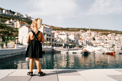 Rear view of woman standing against river