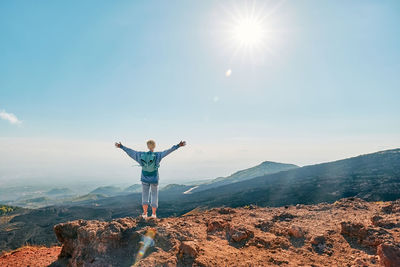 Tourist woman enjoying freedom with open hands, while admiring panoramic view of volcano etna.