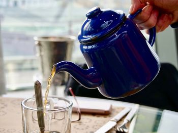 Close-up of hand pouring tea cup