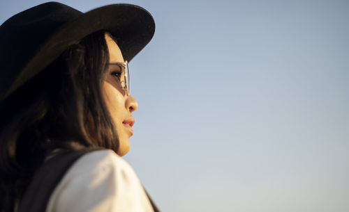 Portrait of young woman looking away against sky