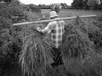 Rear view of man holding umbrella on field