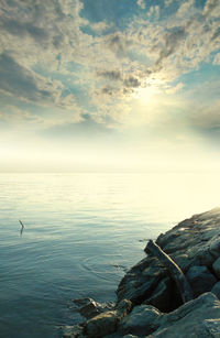 High angle view of rocks by sea against cloudy sky