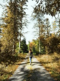 Rear view of man walking on road amidst trees