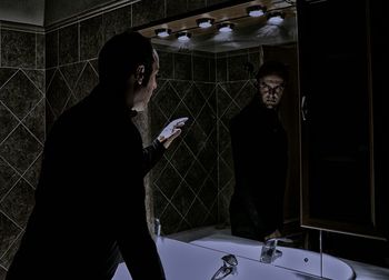 Serious man gesturing on mirror in bathroom