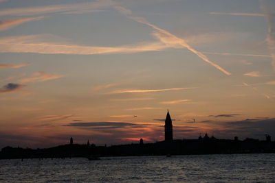 Silhouette of building by river during sunset