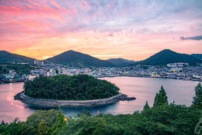 Scenic view of sea by city against sky at sunset