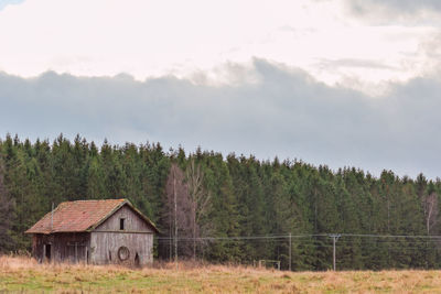 Barn by trees against sky