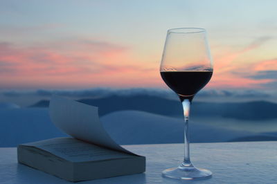 Close-up of beer on table against sea during sunset