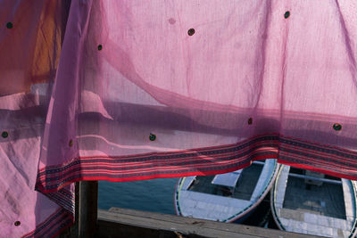 Full frame shot of wooden boats on the ganges, framed by sari hanging from railing.