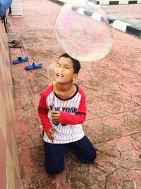 Boy blowing bubble on footpath