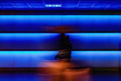 Full length of woman walking in illuminated corridor