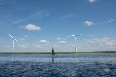 Wind turbines in sea against sky