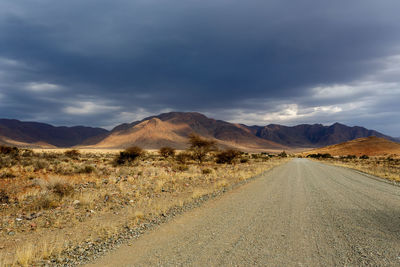 Road leading towards mountains against sky