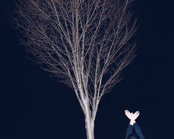 Cropped hands against trees at night