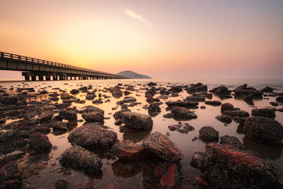 Rocks on shore against sky during sunset