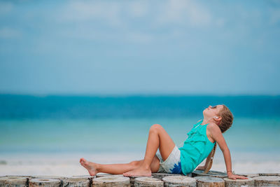 Man relaxing on beach against sky