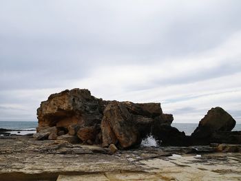 Rock formation on beach against sky