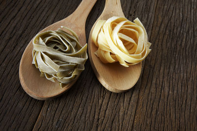 Close-up of tagliatelle pasta in wooden spoons on table