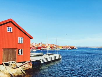 House by sea against buildings against clear blue sky