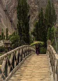 Rear view of man walking on footbridge