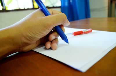 Close-up of hand holding pen on blank paper
