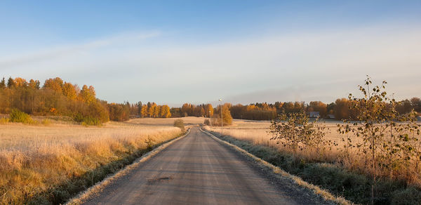 Road amidst field against sky